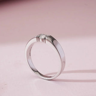 Side angled view of Elegant Minimalist Radiant Diamond Ring in white gold, highlighting a single round lab-grown diamond secured within a sleek flat polished band against a soft pink background.