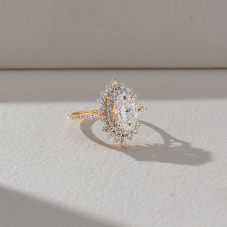 Angled view of Vintage Halo Diamond Ring in 14KT Yellow Gold, featuring an oval lab grown diamond with halo and marquise accents. Set on a beige backdrop, the design highlights depth and ornate brilliance.
