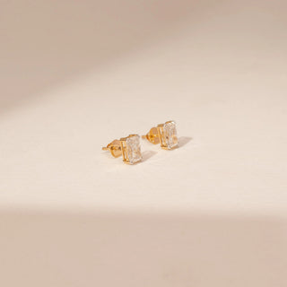Angled view of 14KT White Gold diamond earrings with rectangular-cut centre diamonds in four-prong stud settings.