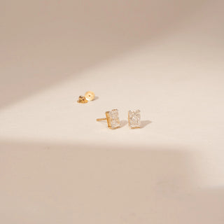 Angled view of 14KT White Gold diamond earrings with rectangular-cut centre diamonds in four-prong stud settings.