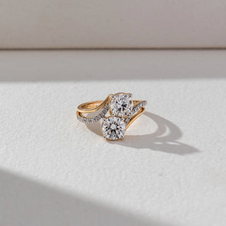 Top view of Dual Round Diamond Ring in 14KT Yellow Gold, featuring two round lab grown diamonds with a pavé crossover band. Set on a beige backdrop, the design highlights symmetry and brilliance.
