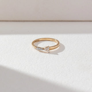 Top view of Round Accent Diamond Ring in 14KT Yellow Gold, featuring a centred trillion-cut lab grown diamond with round accent stones on one side. Set on a beige backdrop, the design highlights minimal elegance and sparkle.
