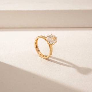 Angled view of a 14KT Yellow Gold ring featuring a cushion diamond in a four-prong setting with a polished gold band.