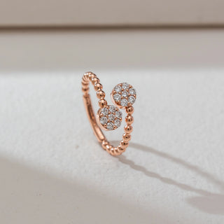 Side angled view of open bead diamond ring in rose gold, featuring two circular cluster heads set with round lab-grown diamonds on a beaded band. Set on a soft neutral backdrop, it highlights texture and sparkle.