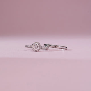 Front view of Timeless Pavé Accented Diamond Ring in white gold, featuring a round lab-grown diamond halo with pavé-set band, displayed alongside a matching band on a soft pink backdrop.