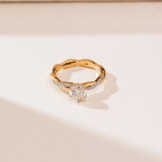 Top view of Braided Twisted Solitaire Diamond Ring in yellow gold, featuring a round lab-grown diamond set on an intertwined twisted band with delicate diamond accents, placed on a soft beige backdrop.