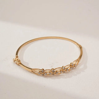 Angled view of yellow gold infinity wave diamond bracelet featuring interwoven loops set with round lab-grown diamonds, displayed on a soft neutral background highlighting its elegant flow.