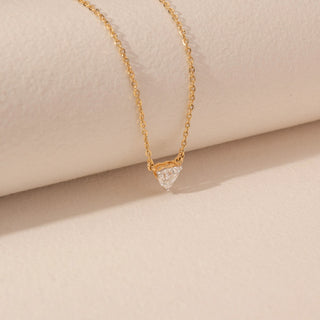 Side view of a 14KT yellow gold necklace featuring a heart-cut diamond pendant, set against a beige background.
