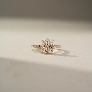 Front view of a floral diamond ring featuring marquise and round diamonds arranged in a flower motif, set on a slim diamond-studded band in warm-toned gold.
