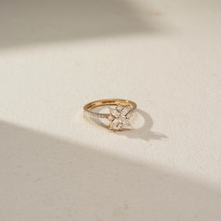 Top view of a floral diamond ring featuring marquise and round diamonds arranged in a six-petal flower design, set on a delicate diamond-accented gold band.