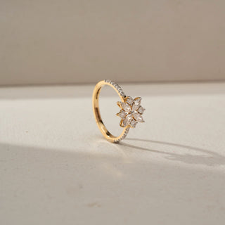 Angled view of a yellow gold floral diamond ring featuring marquise and round-cut diamonds in a flower motif, with a delicate pavé-set band, displayed in soft natural light.