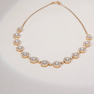 Top view of a floral lab-grown diamond necklace in 14KT Yellow Gold, featuring round diamond cluster motifs linked by bezel-set accents. Captured against a beige backdrop, the elegant design radiates timeless brilliance.