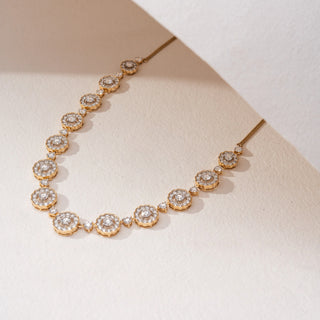 Angled view of a floral lab-grown diamond necklace in 14KT Yellow Gold, featuring round diamond cluster motifs linked by bezel-set accents. Captured against a beige backdrop, the elegant design radiates timeless brilliance.