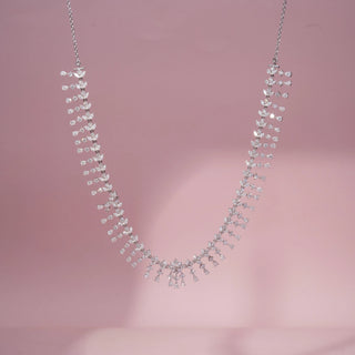 Front view of a floral lab-grown diamond necklace in 14KT White Gold, featuring cascading pear-shaped diamond motifs in a graceful fringe design. Captured against a pink backdrop, the elegant silhouette radiates brilliance.