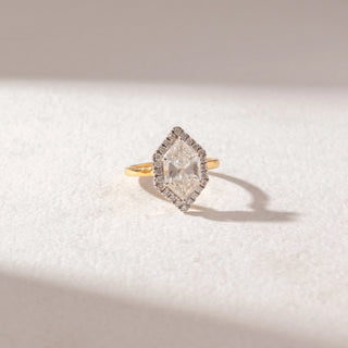 Top view of Hexagon Halo Diamond Ring in 14KT Yellow Gold, featuring a large center diamond encircled by a pavé halo. Set on a soft beige surface, the design reflects refined brilliance and symmetry.
