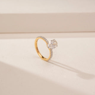 Angled view of a 14KT Yellow Gold diamond ring, featuring oval and pear-shaped diamonds with a diamond-set band.