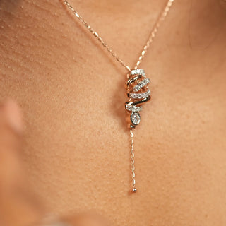 The front view on the neck of the model, wearing a pendant reveals a stunning 0.527-carat diamond with a spring lock of size 16 inches, set in 14 KT rose gold. The pendant features a blooming floral design, with the central diamond elegantly suspended, creating a captivating drop effect. The clean, white background accentuates the intricate craftsmanship and the lab-grown diamonds brilliant sparkle.