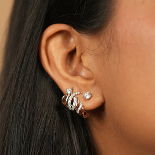 The female earring in 14 KT rose gold weighing a total of 8 grams with a total of 0.848 carats secured through a push and pull mechanism showcased on the model's left ear crafted with meticulous attention to detail, these stunning pieces feature a unique design that is both modern and classic. The shimmering diamonds, meticulously set in a delicate silver frame, create a dazzling display of light and sparkle.