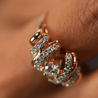 A zoomed-in top view of a female 14 KT rose gold ring of size 12, modelled on a finger, featuring a contemporary flowing design with interwoven rows of rose gold along with lab grown round cut diamonds in prong setting with a total of 0.709 with the solitaire and 0.31 carats, and weighing 5.23 grams, making it perfect for any occasion and everyday wear.