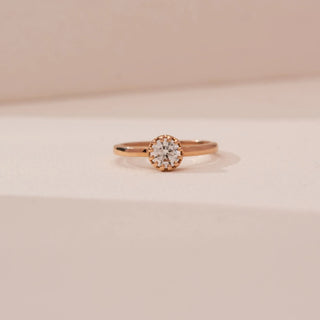 Front view of Reia’s 14 KT Rose Gold Classic Bezel Diamond Solitaire Ring. It showcases the sleek bezel setting and high-polished band against a soft neutral backdrop.