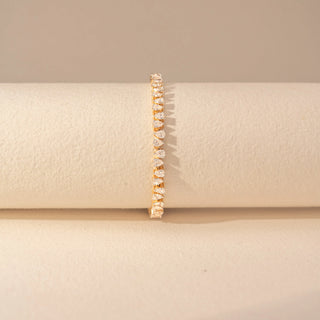 Front view of a 14KT yellow gold bracelet featuring pear-cut diamonds, set against a beige background.