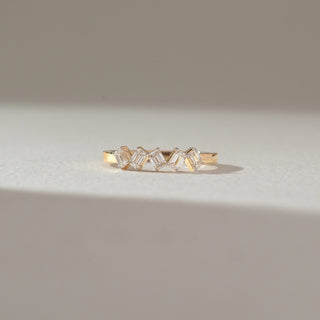 Front view of zigzag baguette diamond ring in yellow gold, featuring a row of lab-grown baguette diamonds set in a sharp geometric pattern. Captured against a soft beige background with gentle shadows.