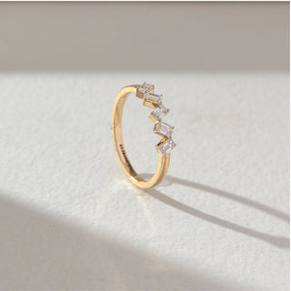 Side profile of zigzag baguette diamond ring in yellow gold, featuring lab-grown baguette diamonds set in a sharp geometric pattern. Captured against a soft beige textured background.