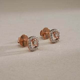 Side view of Dual Halo Diamond Stud Earrings in 14KT Rose Gold, placed on a neutral surface, featuring central EF-VVS round diamonds framed by sparkling halos with secure Bombay screw backs.