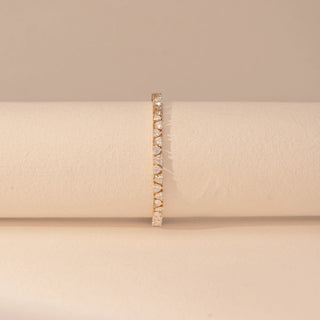 Front view of a 14KT yellow gold bracelet featuring heart-cut diamonds, set against a beige background.
