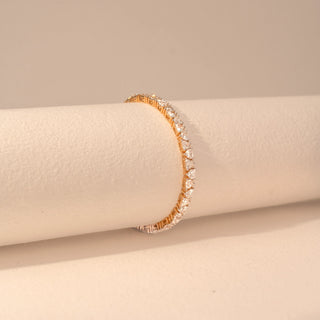 Side view of a 14KT yellow gold bracelet featuring heart-cut diamonds, set against a beige background.