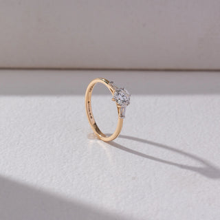Side view of Round Solitaire Diamond Ring in 14KT Yellow Gold, featuring a centred round lab grown diamond with baguette side accents. Set on a beige backdrop, the design highlights structure and refined elegance.
