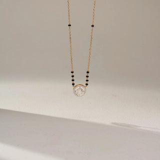 Front view of a yellow gold lab-grown diamond mangalsutra featuring a round halo diamond pendant on a delicate black bead chain, displayed on a neutral background.