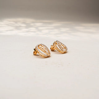 Side view of abstract diamond stud earrings in 14 KT Yellow Gold, featuring layered pavé-set oval frames with clustered marquise and pear-shaped diamond accents, displayed on a textured stone surface.
