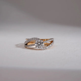 Cross-over diamond ring featuring a round-cut center stone framed by two curved bands lined with small round diamonds, creating a graceful layered design.
