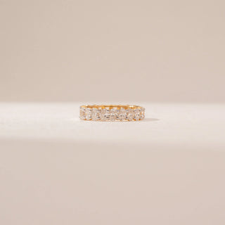 Front view of a oval diamond eternity ring in 14KT Yellow Gold, featuring a continuous row of oval diamonds against a beige backdrop.