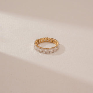 Top view of a oval diamond eternity ring in 14KT Yellow Gold, featuring a continuous row of oval diamonds against a beige backdrop.