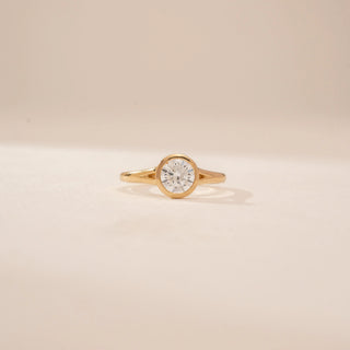 Close-up view of a 14KT Yellow Gold diamond ring with a round bezel-set diamond and slim polished band.