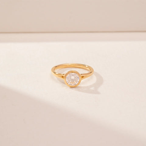 Front view of a 14KT Yellow Gold diamond ring with a round bezel-set diamond and slim polished band.
