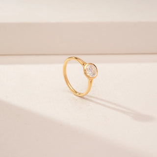 Angled view of a 14KT Yellow Gold diamond ring with a round bezel-set diamond and slim polished band.