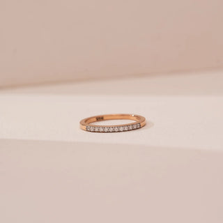 Front view of Reia’s 14 KT Rose Gold Minimal Everyday Ring, showing the continuous shimmer of round diamonds. Captured against a cream backdrop, the layout highlights the approachable elegance.