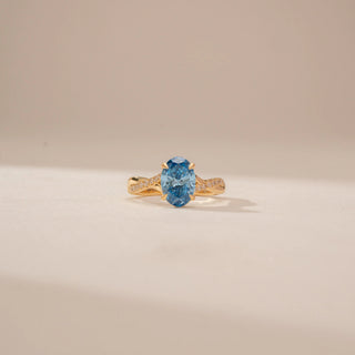 Front view of a 14KT Yellow Gold diamond ring, featuring an oval blue centre stone and diamond-set shoulders.