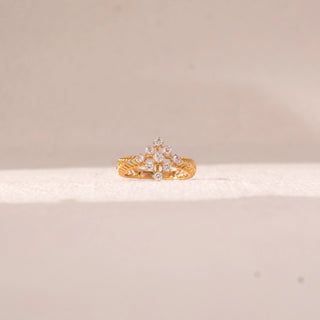 Front view of floral cluster diamond ring in yellow gold, featuring round lab-grown diamonds arranged in a blooming cross motif atop a textured band. Set against a soft beige backdrop, the design reflects delicate brilliance.