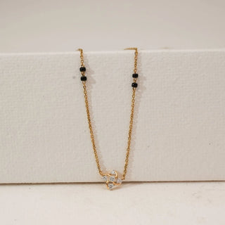 Front view of petite floral diamond mangalsutra in yellow gold, featuring a delicate blossom pendant with round lab-grown diamonds and a fine chain accented with traditional black beads.