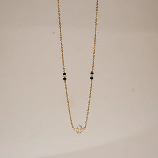 Front view of delicate gold mangalsutra featuring a petite floral diamond pendant with round lab-grown diamonds, suspended on a fine yellow gold chain accented with traditional black beads.