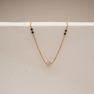 Front view of elegant gold mangalsutra with petite floral diamond pendant crafted with round lab-grown diamonds, suspended on a fine yellow gold chain highlighted by traditional black bead accents.