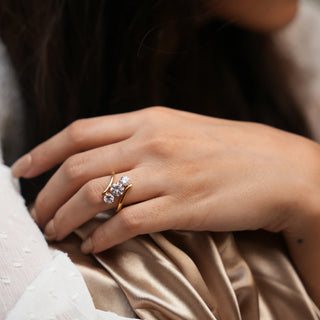 A zoomed-out version of an elegant three-stone diamond ring features three sparkling round-cut lab-grown diamonds, set in a unique curved gold band. The diamonds are arranged in a staggered pattern. This ethically sourced piece is perfect for any occasion, from everyday wear to special events. Close-up view of a model's hand, the Diamond female ring of size 14 boasts 1.9 carats of stunning lab-grown diamonds, set in 18 KT yellow gold weighing a total of 4.52 grams.