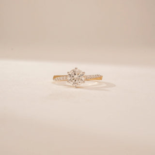 Front view of a 14KT Yellow Gold diamond ring, featuring a round centre diamond and diamond-set shoulders.