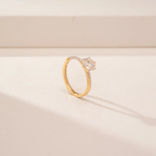Angled view of a 14KT Yellow Gold diamond ring, featuring a round centre diamond and diamond-set shoulders.