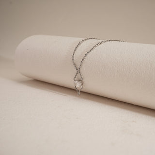 Flat display of Dainty Infinity Solitaire Drop Necklace on a soft beige surface, showcasing its 14 KT white gold chain and solitaire diamond pendant with EF colour, VVS clarity stones totaling 0.78 carats.