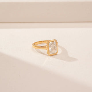 Side view of a 14KT Yellow Gold diamond ring, featuring a rectangular step-cut centre diamond in a bezel setting.